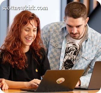 Two SiteGround employees collaborating and smiling while working together on a laptop.