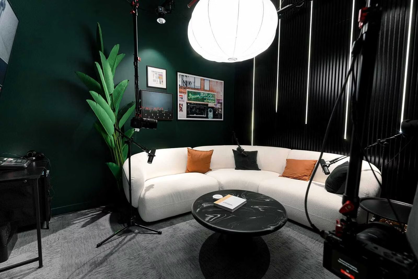 Kit Studios Chicago recording room with white curved sofa, professional lighting and camera equipment, and Chicago-themed wall art